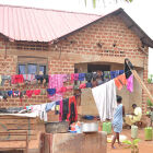 Jajja Flora&#039;s home from where she looks after several children.<br />In a small, muddy courtyard three kids are playing while a woman washes away a heap of clothes.